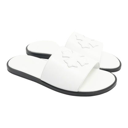 OFFCODE.USA white leather slides featuring a decorative cross patch detail on the strap and a black sole.
