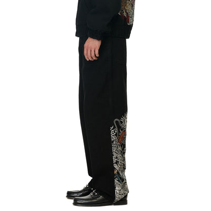 OFFCODE.USA black denim balloon fit jeans with intricate dragon embroidery on the side.