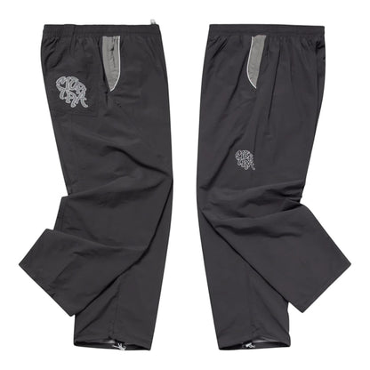 OFFCODE.USA Grey two-tone nylon track pants with applique mesh logo, hidden zipper pockets, and ankle toggles.