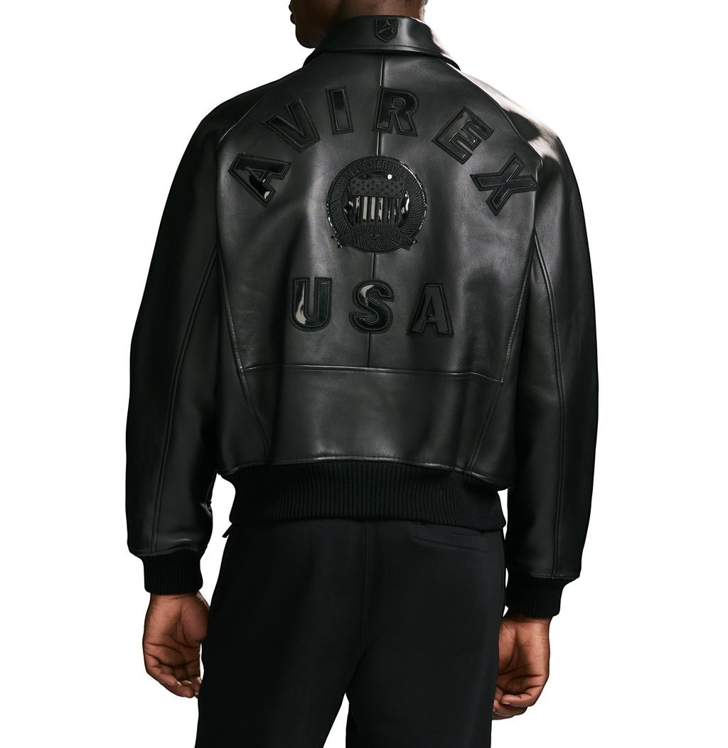 OFFCODE.USA black leather bomber jacket with "AVIREX USA" logo detail on back. Ribbed hem and cuffs.